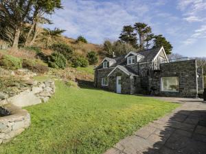 巴茅思Ceilwart Cottage的一座石头房子,位于一座小山上,有院子
