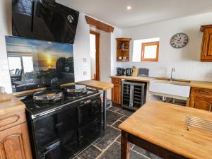 巴茅思Ceilwart Cottage的厨房配有黑炉和水槽。