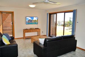 西南岩Seaview Townhouse 3的客厅配有两张黑色沙发和一台电视机
