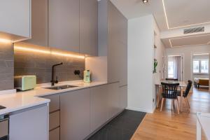 里斯本Charming Design Apartment的一间厨房,配有白色橱柜和一间餐厅
