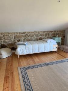 蒙桑图Casa da Avó Maria的卧室配有白色的床和石墙