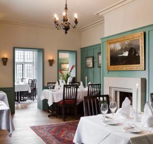 基洛格林Ard na Sidhe Country House Hotel的一间设有白色桌子和壁炉的用餐室