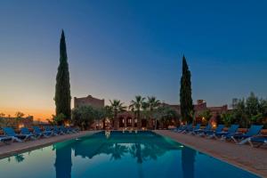 泰赫瑙特卡斯巴安古尔酒店的一个带椅子和棕榈树的游泳池,并可欣赏日落美景