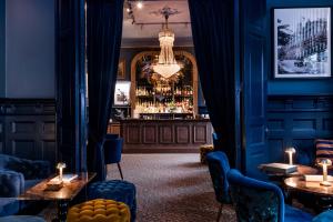 瓦尔贝里瓦尔贝里斯城市酒店及亚洲Spa的一间酒吧,拥有蓝色的墙壁和桌子,配有吊灯