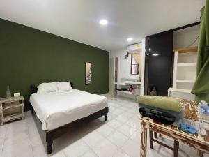 普拉亚卡门Calaveritas Rooms的一间卧室设有一张床和绿色的墙壁