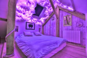 曼特农ALiCe Au PaYs dEs MerVeiLLeS的一间紫色照明客房内的一张床卧室