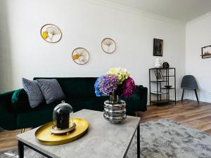 施塔德Das Stader Domizil的客厅配有绿色沙发和鲜花的桌子