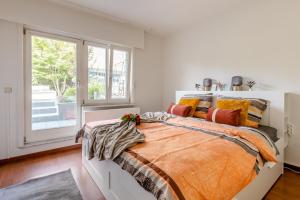 安特卫普Luxe apt with parking & garden in wilrijk antwerp的一间卧室配有一张带橙色棉被的床和窗户