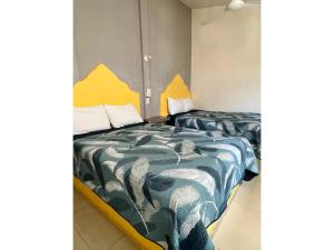 圣克鲁斯华特库Hotel Ocean Huatulco的小客房内的两张床,配有黄色和蓝色的床单
