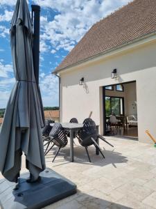 拉罗什波赛Maison contemporaine au cœur de la Roche-Posay的露台配有遮阳伞、椅子和桌子