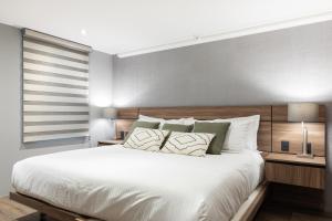 墨西哥城Capitalia - Apartments - Polanco - Julio Verne的卧室配有一张白色大床和木制床头板