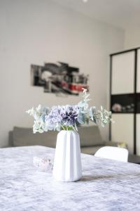 霍伊尼采Apartament "Przy Dworcu"的白色花瓶,花紫色坐在桌子上
