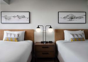 尔湾Sonesta Irvine的一间卧室配有两张床,还有一个床头柜和两盏灯。