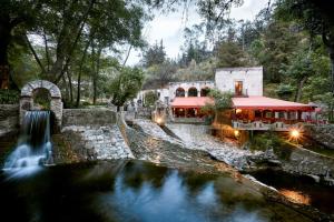 TotolacMolino de los Reyes By Rotamundos的河边有瀑布的建筑