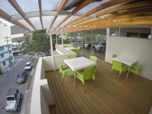 帕斯托Hotel Parque Reservado的大楼内的阳台配有绿色的桌椅