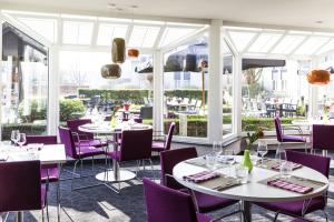 布雷达布雷达诺富特酒店的餐厅配有白色桌子和紫色椅子