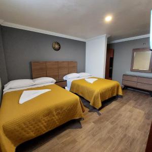 托卢卡Hotel Santino的配有黄色床单的酒店客房的两张床