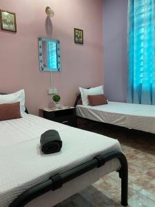 Kampong TamanSeri Idaman Guest House (Pasir Mas)的一间设有两张床的房间,床上有一顶帽子