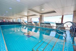 长滩岛钻石水畔度假酒店的一个带椅子的游泳池,背景是大海