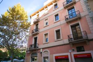 巴塞罗那Decô Apartments Barcelona-Sants的一座粉红色的建筑,旁边设有阳台