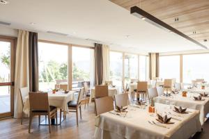 马兰扎Family Home Alpenhof的餐厅设有白色的桌椅和窗户。