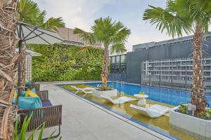 新加坡Citadines Connect City Centre Singapore的一个带棕榈树和躺椅的室外游泳池
