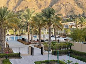 马斯喀特Stylish Apartment with a Jacuzzi (Park&Pool View)的棕榈树和山 ⁇ 的度假村
