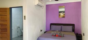 珍南海滩OCEAN LODGE的一间卧室设有紫色的墙壁和一张带凉鞋的床。