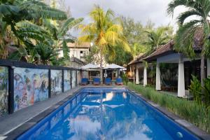 吉利特拉旺安Warna Beach Hotel的棕榈树屋前的游泳池