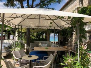 苏佩塔尔Apartments by the sea Supetar, Brac - 11497的一个带桌椅的白色遮阳伞下庭院