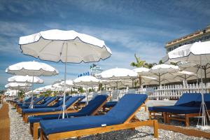 尼斯阿斯顿斯卡拉酒店的海滩上的一排躺椅和遮阳伞