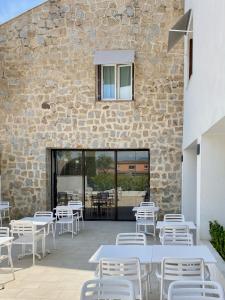 波尔蒂乔博迪西欧酒店的石墙旁的庭院配有白色的桌椅