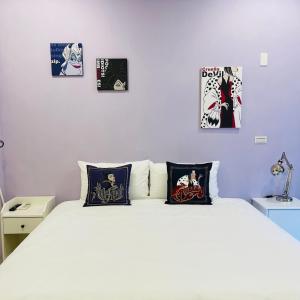 台南唐揚十二街的卧室配有一张白色床,墙上挂有4张照片
