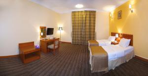 艾恩Al Massa Plus Hotel的酒店客房配有两张床和一张书桌