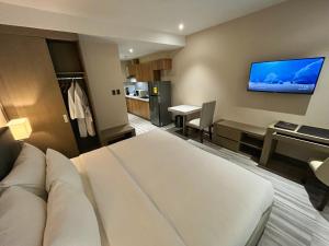 安吉利斯Capitol Hill Hotel and Suites的酒店客房设有一张床和墙上的电视
