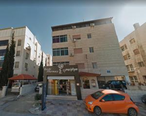 Umm UthainahLovely Two Bedroom Apartment in Amman的停在大楼前的橙色汽车