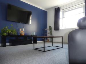邓弗里斯Dumfries Apartment的客厅配有桌子和蓝墙上的电视