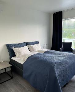 StonglandseidetSenja Living的一间卧室配有一张带蓝色棉被的床和窗户。