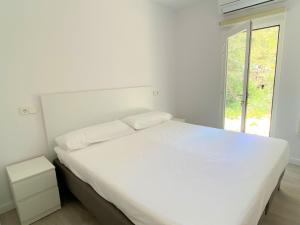 埃斯卡洛Can Valonsadero, Villa con Piscina的白色的卧室设有白色的床和窗户。
