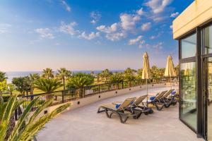 坎波菲利斯·迪·罗切Grand Palladium Sicilia Resort & Spa的阳台上的一排躺椅和遮阳伞
