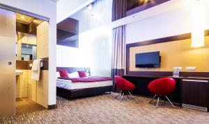 扎布热迪雅门特扎布热公园酒店 - 格利维采的酒店客房,配有一张床和两张红色椅子