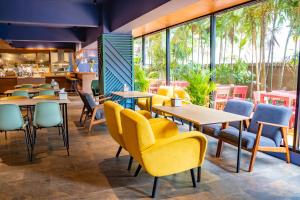 莱卡邦素万那普村舍酒店的餐厅设有桌椅和窗户。