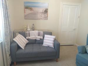 科芙Sea View Cottage, 2 bedrooms with stunning views的客厅配有带条纹枕头的蓝色沙发