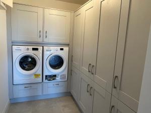 加尔伊沃耶Garryvoe - Ballycotton Bay & Island View的洗衣房配有白色橱柜、洗衣机和烘干机