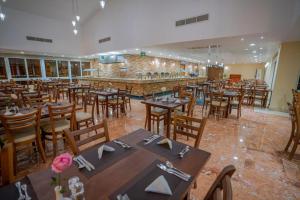 艾因苏赫纳Blumar El Dome Hotel的一间带木桌椅的餐厅和一间酒吧