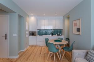 里斯本Ajuda Luxury Appartments的厨房以及带桌椅的起居室。