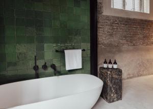 马斯特里赫特Cousins Boutique Hotel的浴室设有白色浴缸和绿色瓷砖墙。