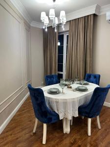 阿拉木图Apartments in the Babylon residential complex的一间配备有白色桌子和蓝色椅子的用餐室