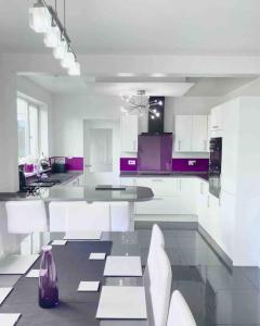 庞蒂浦Caithness Holiday Home的白色的厨房配有紫色橱柜和桌子