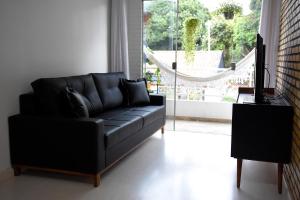 巴西利亚FLAT W3 Norte的客厅里设有一张黑色皮沙发,配有窗户